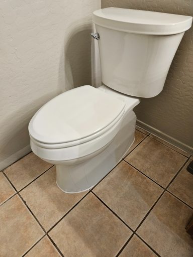 Toilet on a tiled floor White toilet installed on a tiled bathroom floor