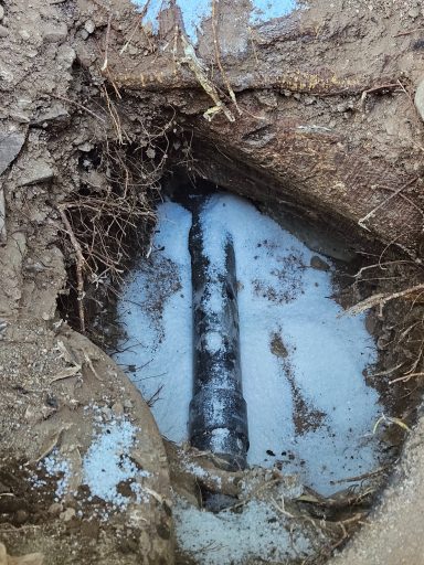 Underground pipe inspection Exposed underground pipe in a trench with standing water