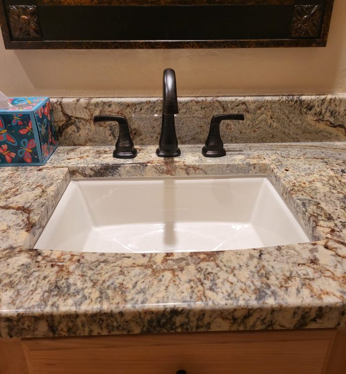 Completed bathroom fixture installation Installed bathroom sink with a black faucet and stone countertop