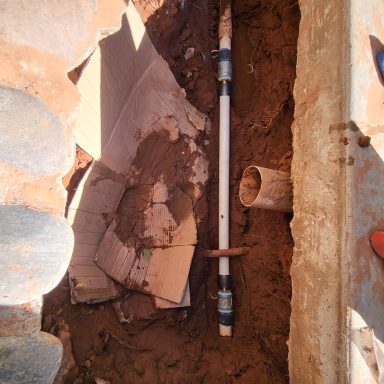 Water line trench detail Open trench beside a concrete walkway with exposed pipe