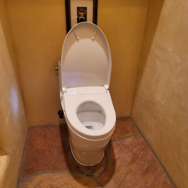 Toilet fixture detail Toilet with the lid open in a tiled bathroom alcove