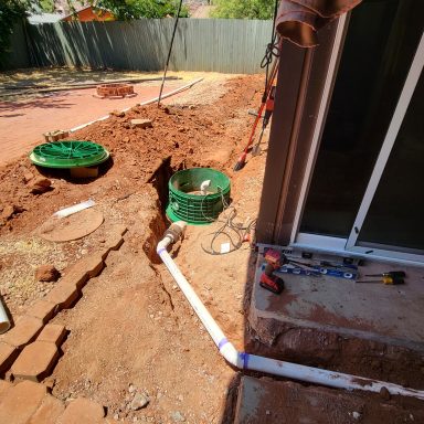 Underground plumbing access Excavated plumbing beside a home with green access covers