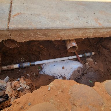 Exposed underground plumbing Excavated area beneath a concrete slab with exposed piping